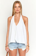 a brunette girl wears a white top with a low back, sunglasses and denim mini skirt holding a drink